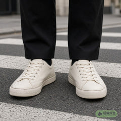 Off-white canvas sneakers worn on a city street crossing