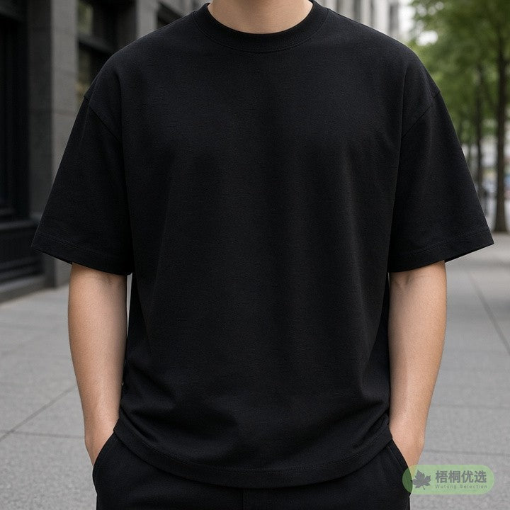 Person wearing a black oversized tee on a city sidewalk, face not shown