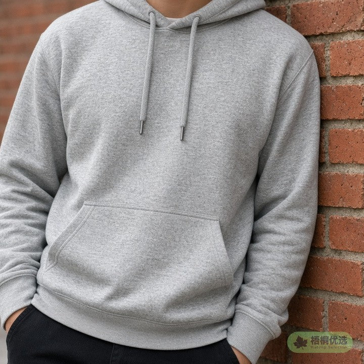 Person in a grey hoodie leaning on a brick wall, face not shown